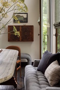 a living room filled with furniture next to a wooden table and wall mounted planter