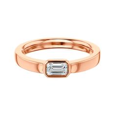 a rose gold ring with a baguette cut diamond in the center, on a white background