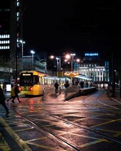 people crossing the street in front of a train at night