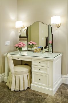 a vanity with a stool and mirror in a room next to a wall mounted light