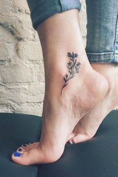 a woman's foot with a small flower tattoo on her left ankle and blue nail polish