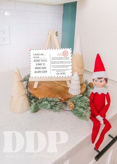 an elf sitting on top of a counter next to a sign