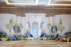 an elaborately decorated stage with blue and yellow flowers on the floor, in front of a white wall