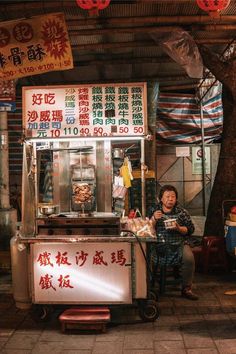 a man sitting in front of a food cart