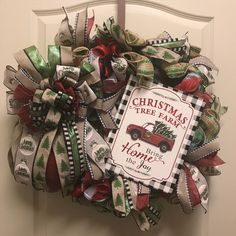 a christmas tree farm wreath hanging on the front door with ribbon around it's edges