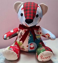 a teddy bear with a red bow on its neck and plaid fabric covering it's face