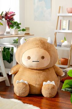 a large stuffed animal sitting on top of a wooden floor next to a potted plant