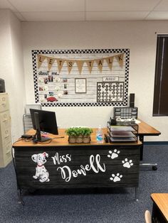 an office cubicle with a desk, computer and dog paw prints on the wall