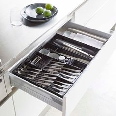 an open drawer with utensils and silverware in it on a countertop