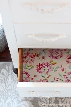 an open drawer with floral wallpaper on the bottom and side drawers in front of it