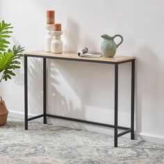 a table with a potted plant on it next to a vase and other items