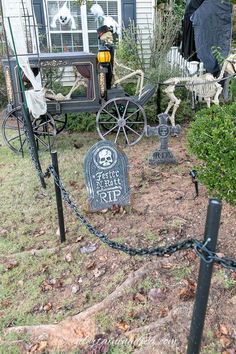 halloween decorations in front of a house with skeletons on the lawn and skeleton statues behind them