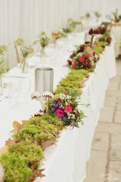 the long table is covered with moss and flowers