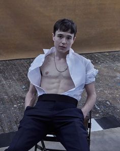 a man sitting in a chair with his shirt open