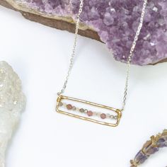 Our Elegance Kaleidoscope Necklace is a mesmerizing fusion of color and sophistication. At its heart, a handcrafted gold rectangle pendant becomes a canvas for a splendid array of tiny tourmaline, moonstone, and labradorite gemstones, forming a kaleidoscope of hues that gracefully stretches across the pendant's interior. Each gemstone, with its unique color and iridescence, captures the essence of natural beauty. The pendant hangs delicately from a fine silver chain, adding a touch of modern ele Rectangular Gold Artisan Jewelry, Artisan Rectangular Gold Jewelry, Dainty Rectangular Gemstone Jewelry, Dainty Handmade Rectangular Jewelry, Handmade Dainty Rectangular Jewelry, Spiritual Rectangular Gemstone Beads Jewelry, Rectangular Gemstone Spiritual Jewelry, Bohemian Rectangular Healing Jewelry, Rectangular Tourmaline Gemstone Jewelry