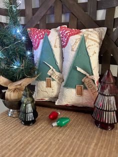 two decorative christmas trees sit next to each other on a table with candles and ornaments