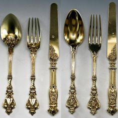 four different types of gold colored forks and spoons with ornate designs on the sides