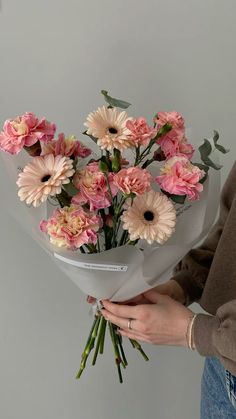 a woman holding a bouquet of pink and white flowers