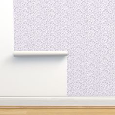 an empty room with a white wall and purple flowered wall paper on the wall