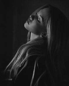 a black and white photo of a woman with long hair looking up at the sky