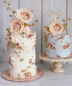 two cakes with flowers on them sitting next to each other in front of a white wall