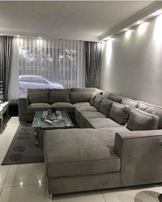 a living room filled with lots of couches and a large tv mounted to the wall