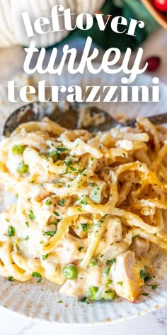 a white plate topped with pasta covered in cheese and sauce next to a spoon on a table