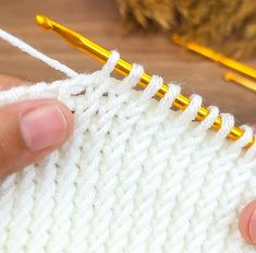 someone is crocheting the stitchs on a white knitted piece with yellow needles