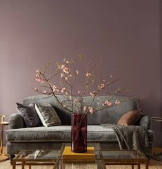 a living room with a couch, coffee table and flowers in a vase on it