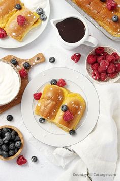 some blueberries and raspberries are on the plate next to other desserts