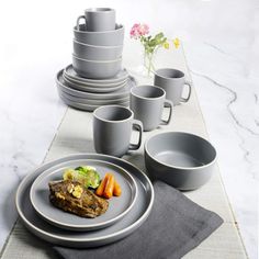 a table set with plates, cups and utensils on top of a place mat