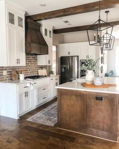 a large kitchen with white cabinets and wood flooring is seen in this image from the front door