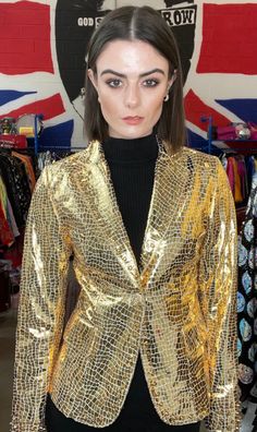 a woman wearing a gold jacket and black top