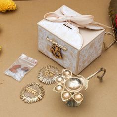 a box that has some items in it on a table next to flowers and brooches