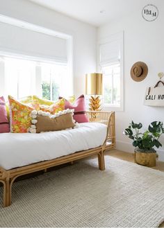 a living room with a white couch and colorful pillows on the top of it's back