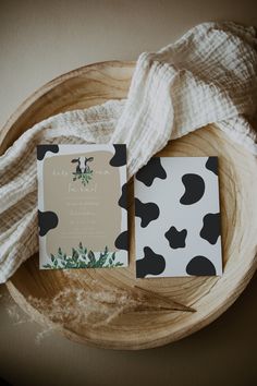 two black and white cards sitting on top of a wooden bowl next to a blanket