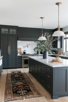 a kitchen with an area rug on the floor and black cabinets in front of it