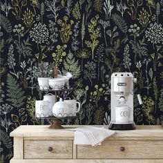 a coffee machine sitting on top of a wooden dresser next to a wall with plants