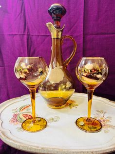 three wine glasses sitting on top of a table next to a pitcher and two goblets