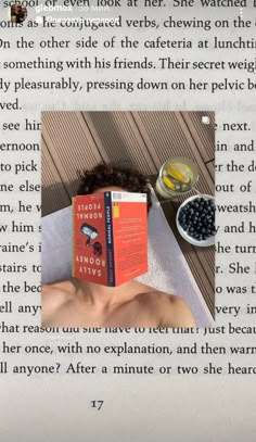 a person laying down with a book in front of their face and food on the table