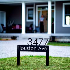 a black and white house number sign sitting in front of a lawn with green grass