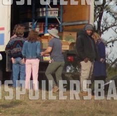 group of people standing in front of the back of a truck