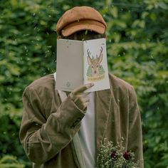 a man holding up a book with a deer on it's face in front of his face