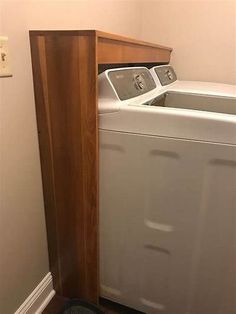 a washer and dryer in a small room with wood paneling on the floor