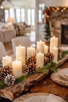 a wooden table topped with lots of white candles and pineconis on top of it