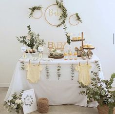 a baby shower table with greenery and cake