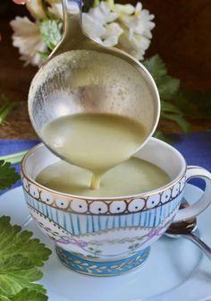 a spoon pouring liquid into a cup filled with soup