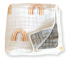 a white blanket with an orange and yellow rainbow design on the front, folded in two rows