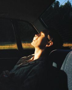 a man sitting in the back seat of a car with his eyes closed looking up