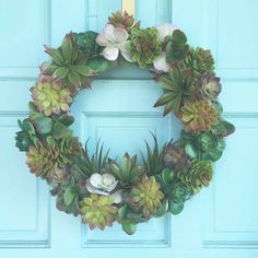 a wreath with succulents and flowers on a blue door